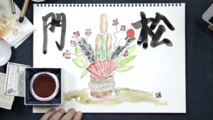 Traditional Japanese shochikubai painting with calligraphy on a sketchpad, featuring plum blossoms, pine, and bamboo, the symbols of perseverance, longevity, and flexibility, alongside an ink stone and brushes, indicating an artistic setting.