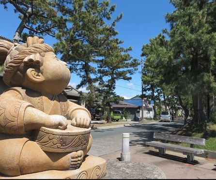 Carved stone statue in a park with pine trees